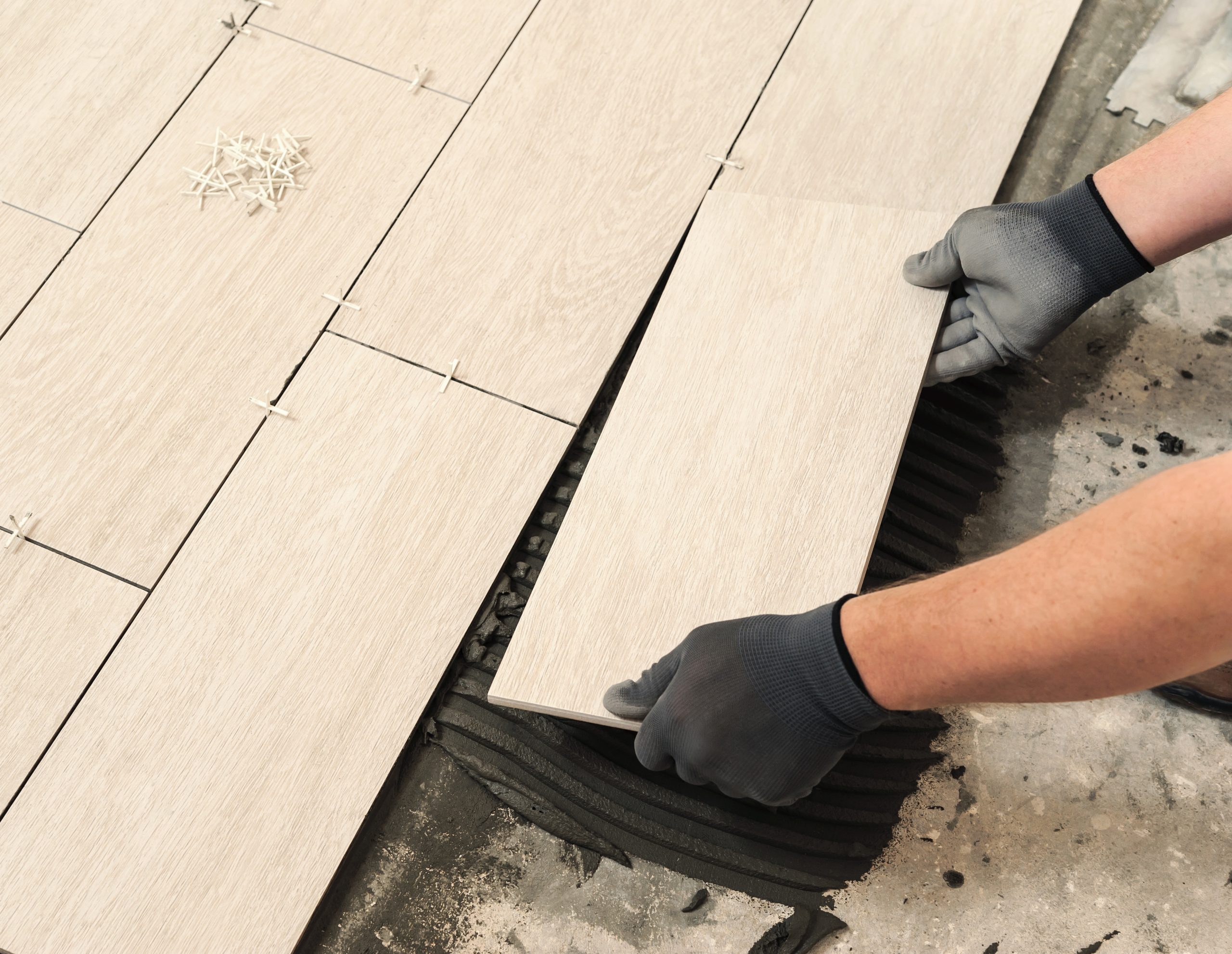 Laying Ceramic Tiles. Man placing ceramic floor tile in position over adhesive